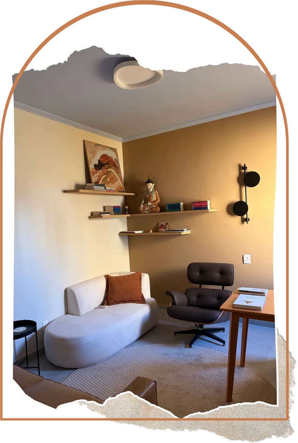 Consultório de atendimento com chaise, poltrona, escrivaninha e prateleiras de livros